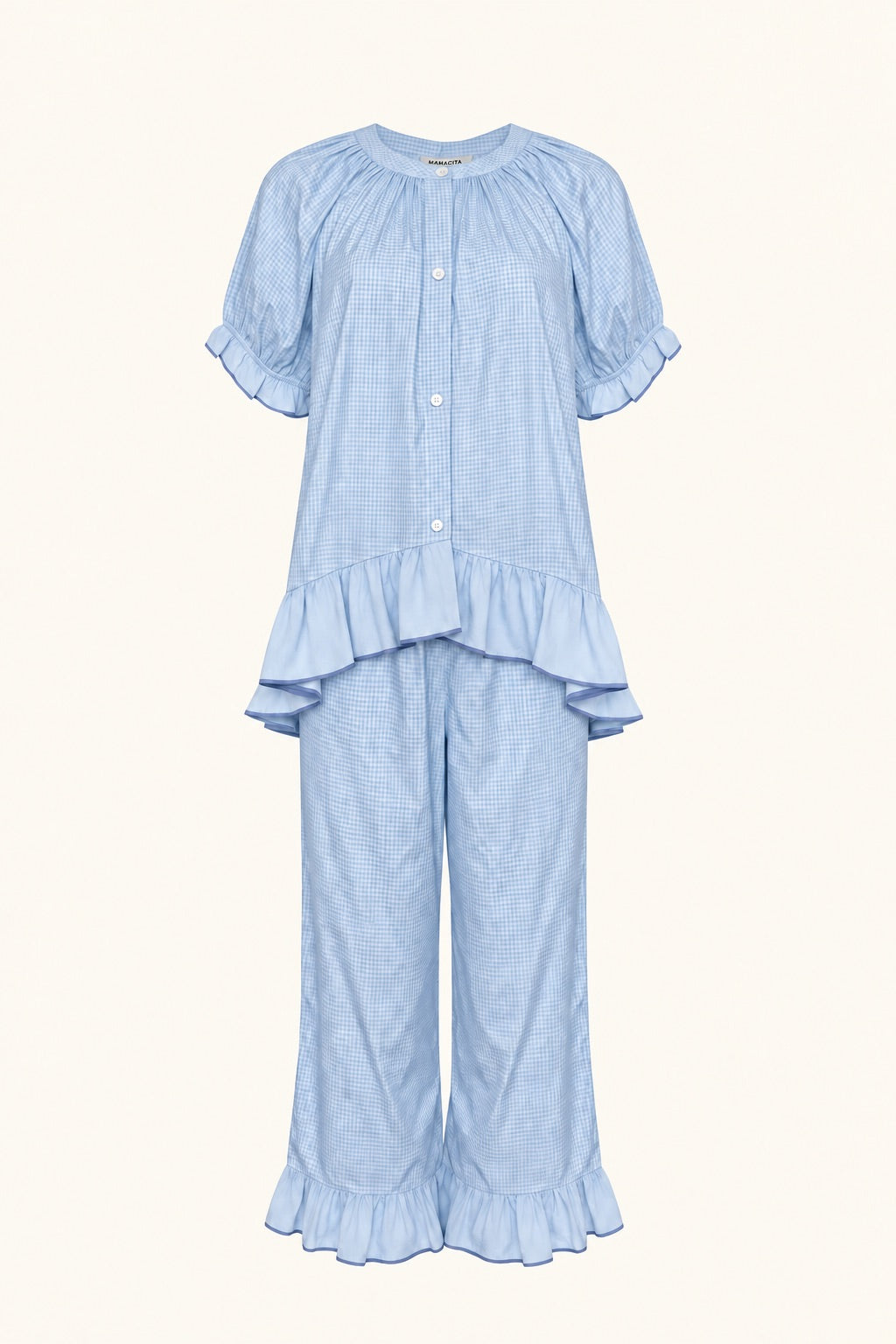 A light blue two-piece pajama set featuring a short-sleeve button-front top with ruffle trim and matching wide-leg pants with ruffle hems, shown on a solid cream background.