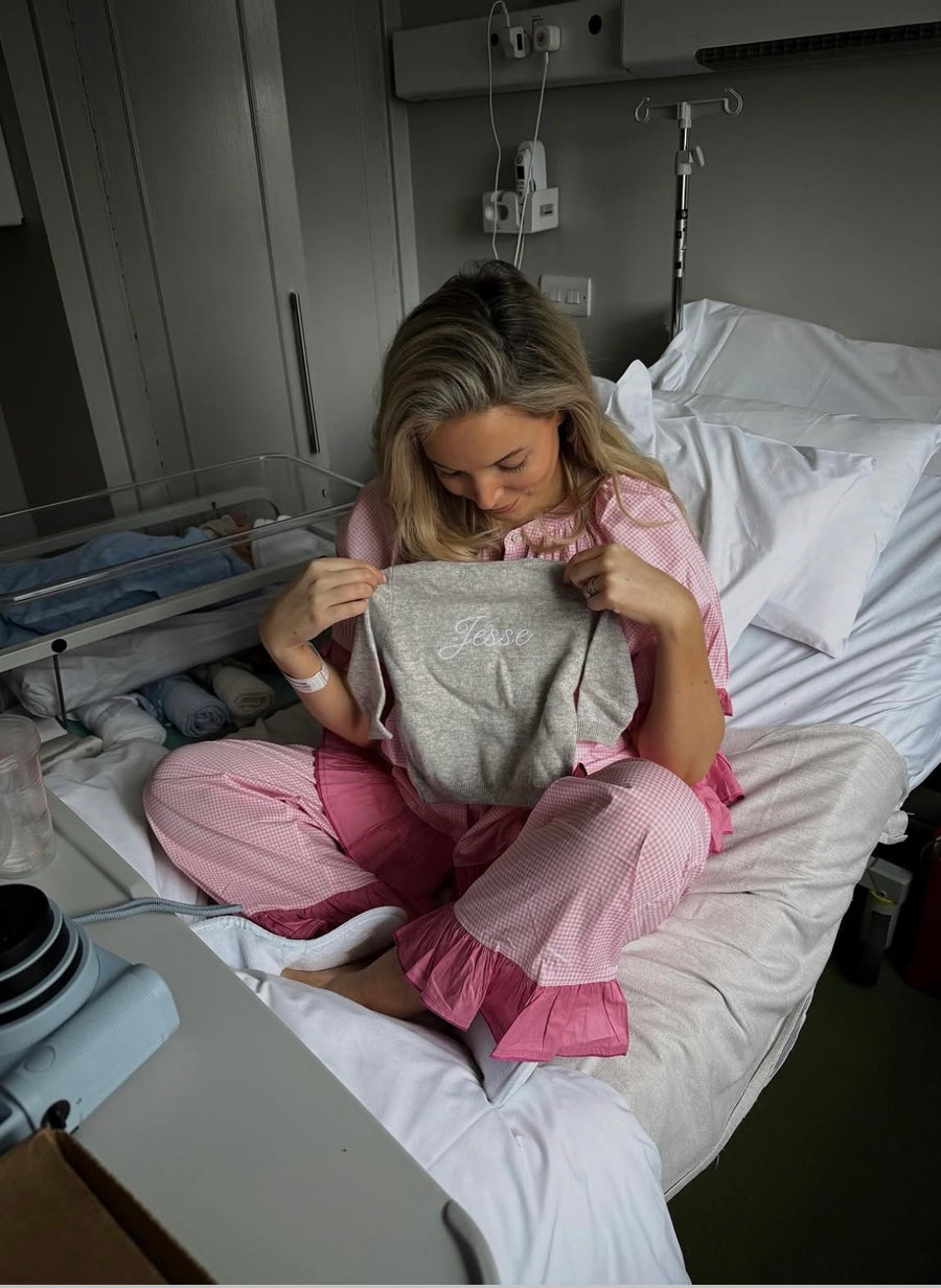 Bonnie Soft Rose sleep set worn while sitting on a bed, showing the ruffled trousers.